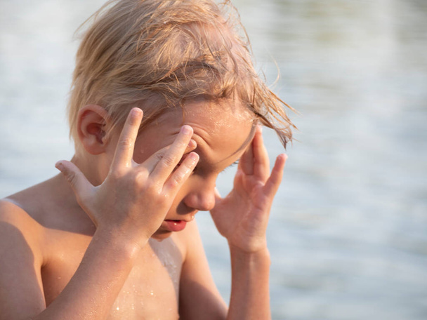 Caucasian preschooler boy with wet hair shakes water from his face while swimming on the lake - Fotografie, Obrázek