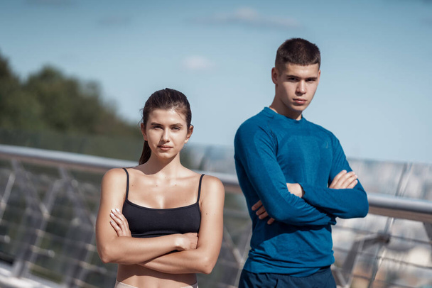 Portret spokojnej dorosłej sportowca stojącej razem po treningu sportowym na świeżym powietrzu patrzącej razem na kamerę, skrzyżowane dłonie na klatce piersiowej - Zdjęcie, obraz