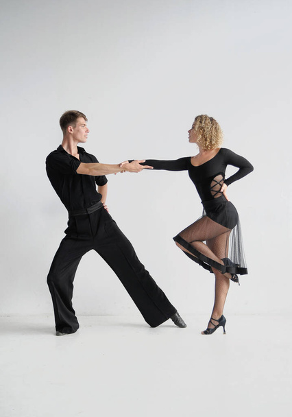 Mooi paar in stijlvolle zwarte kostuums dansen ballroom dansen - Foto, afbeelding