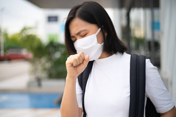 Азиатка в защитной маске от вируса и загрязнения, кашляет и стоит в универмаге. Новый образ жизни с Corona Virus COVID-19. - Фото, изображение