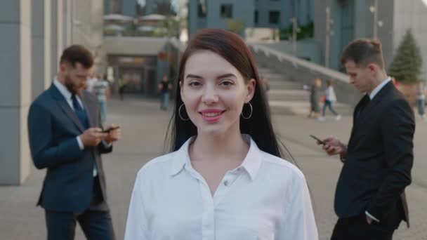 Портрет красивої і впевненої молодої жінки в офіційному костюмі, що стоїть на відкритому повітрі і позує на камеру з щасливою посмішкою в діловому районі міста
 - Кадри, відео