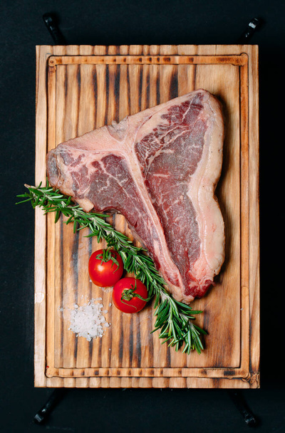 Raw meat steak t-bone on a black background. - Fotoğraf, Görsel