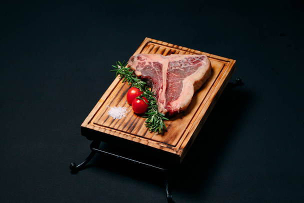 Raw meat steak t-bone on a black background. - Foto, afbeelding