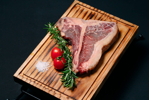 Raw meat steak t-bone on a black background. - Zdjęcie, obraz