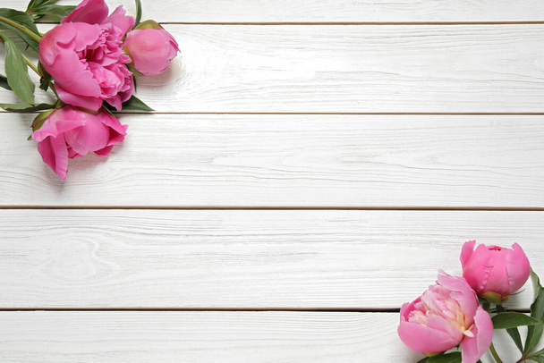 Belles pivoines roses sur fond blanc en bois, couché plat. Espace pour le texte - Photo, image