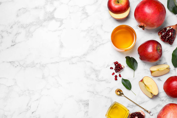 Honey, apples and pomegranates on white marble table, flat lay with space for text. Rosh Hashanah holiday - Foto, Imagen