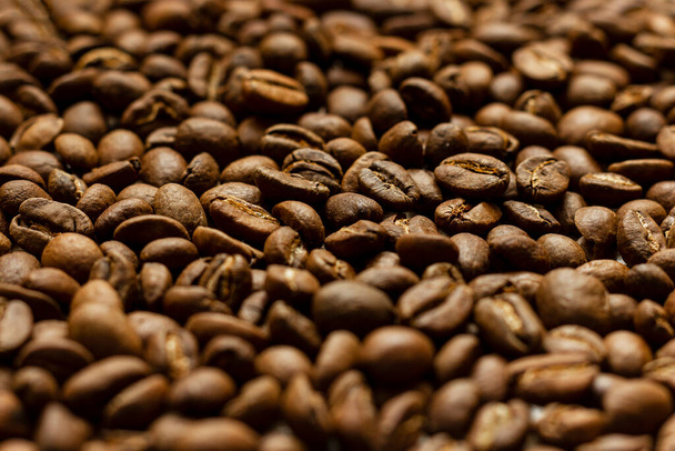 Granos de café tostados dispersos primer plano con primer plano borroso y fondo. - Foto, imagen