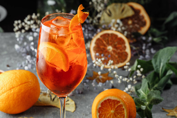 Коктейль Aperol spritz на сером бетонном фоне. стакан апельсинового спрейца с ломтиками апельсина. Летний коктейль в стакане. - Фото, изображение