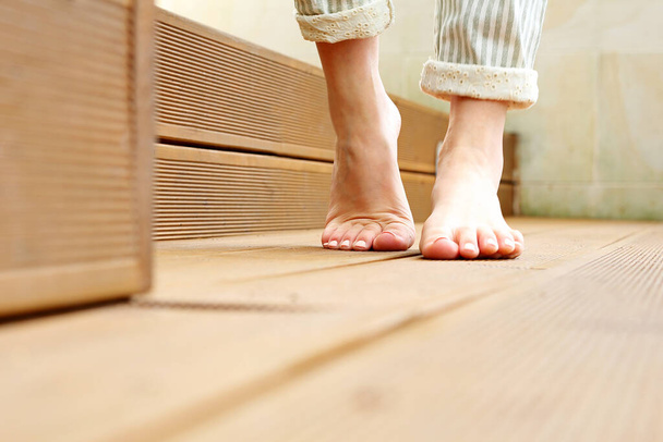 Beautiful bare female feet. A woman is standing barefoot on wooden floorboards. - Valokuva, kuva
