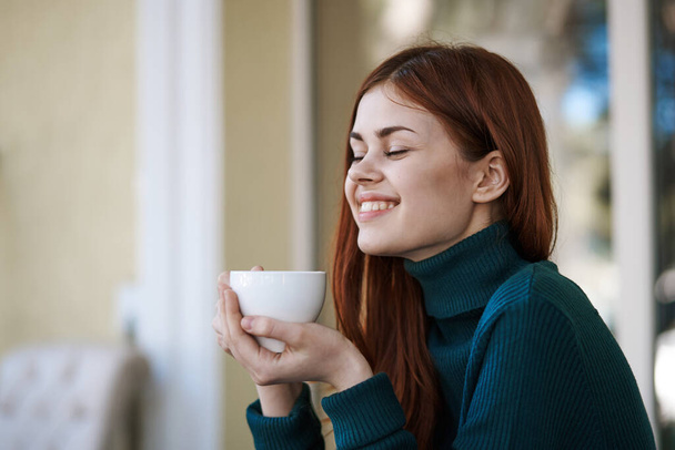 Vörös hajú nő egy utcai kávézóban egy csésze kávéval pihentető - Fotó, kép