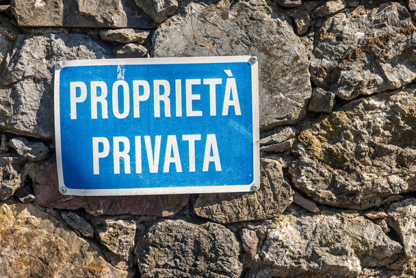 Proprieta Privata, blau-weißes Schild in italienischer Sprache, das an einer Steinmauer hängt. Ligurien, Italien, Europa - Foto, Bild