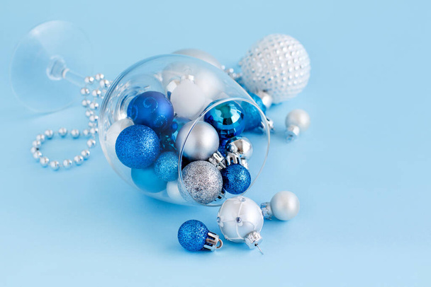Bola de Navidad en una copa de vino sobre un fondo azul claro de cerca - Foto, Imagen