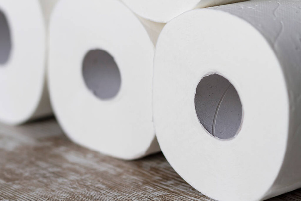 Ένας σωρός από μαλακό χαρτί τουαλέτας κυλά σε ξύλινο φόντο - Φωτογραφία, εικόνα