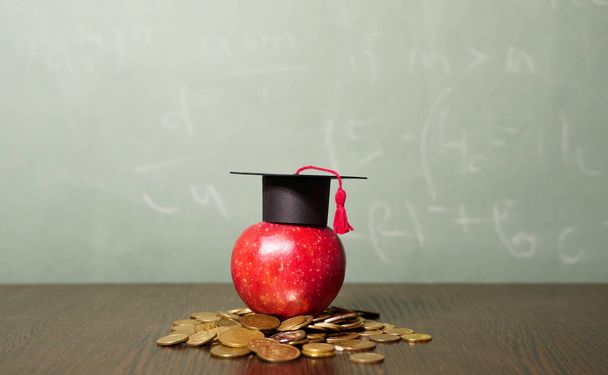 Prestito studenti. La mela rossa in berretto accademico Quadrato rimane su monete. Debito per spese di studio, Borsa di studio universitaria - Foto, immagini