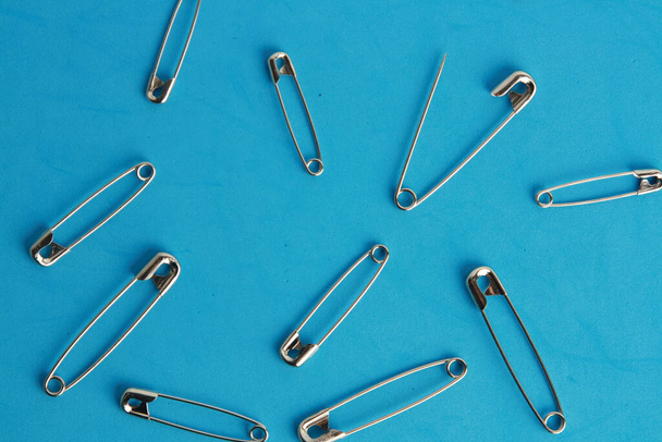 Many sewing pins on a blue background - Foto, imagen