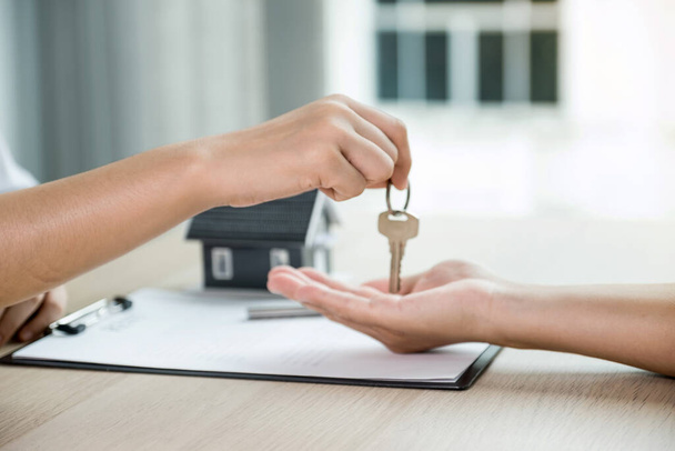 Przekaż agenta nieruchomości, trzymaj klucze i wyjaśnij kupującemu umowę biznesową, wynajem, kupno, hipotekę, pożyczkę lub ubezpieczenie domu. - Zdjęcie, obraz