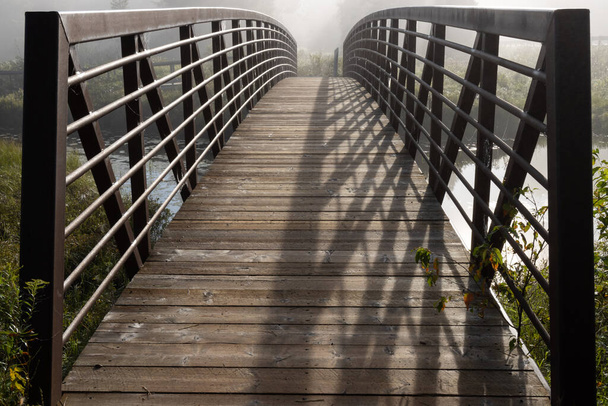 Деревянный пешеходный мост с железным мостом в утреннем тумане - Фото, изображение