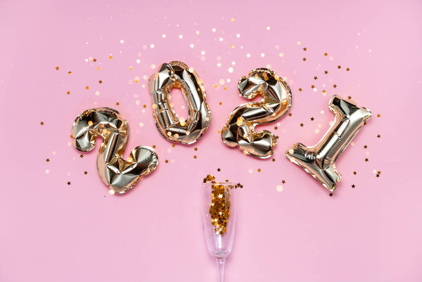2021 gouden folie ballonnen nummers, champagne, sterren confetti, linten en bokeh. Top horizontale weergave kopieerruimte Nieuwjaar en vakantie concept. - Foto, afbeelding