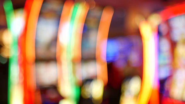 Defokussierte Spielautomaten glühen im Casino auf dem fabelhaften Las Vegas Strip, USA. Verschwommene Glücksspiel-Jackpot-Spielautomaten in einem Hotel in der Nähe der Fremont Street. Leuchtende neonfarbene Spielautomaten für Risikospiele und Wetten. - Foto, Bild