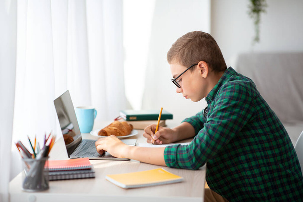 Teenager working hard on homework, online education - Foto, afbeelding