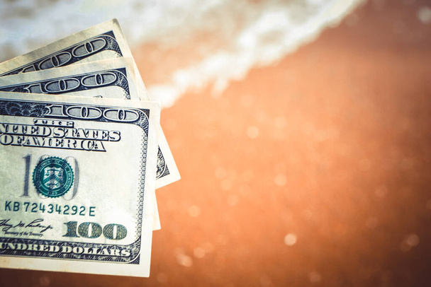 Beyaz köpüklü ve kumlu plajlı deniz dalgalarının arka planında 300 dolarlık banknot tutan bir kız. El dalgasıyla okyanus parası tatili. Mali para seyahati kavramı - Fotoğraf, Görsel