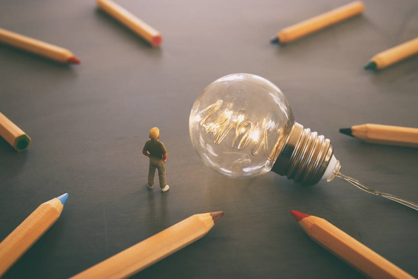 Concept image of child looking at lightbulb and pencils. Education and imagination concept - Фото, зображення