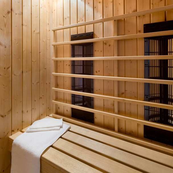 Comfortable wooden finnish style sauna interior with white towels and lights on - Foto, Bild