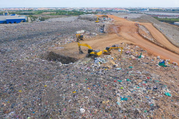 Vue aérienne de la pile de différents types de gros tas d'ordures de montagne, sacs en plastique, et les ordures avec une voiture tracteur dans l'usine industrielle dans la pollution de l'environnement. Élimination des déchets dans les décharges. - Photo, image