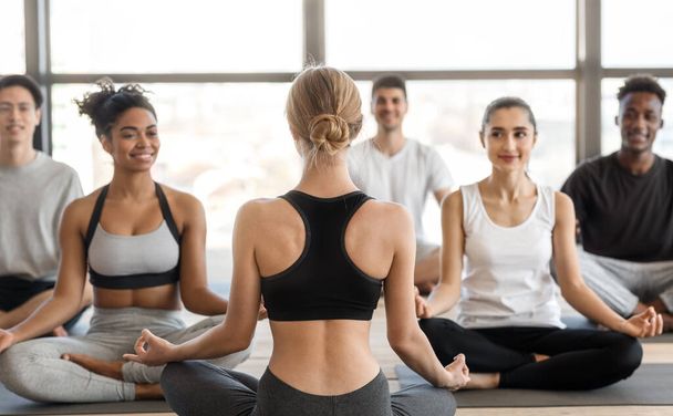 Groupe d'hommes et de femmes multiculturels pratiquant le yoga avec instructeur en studio - Photo, image