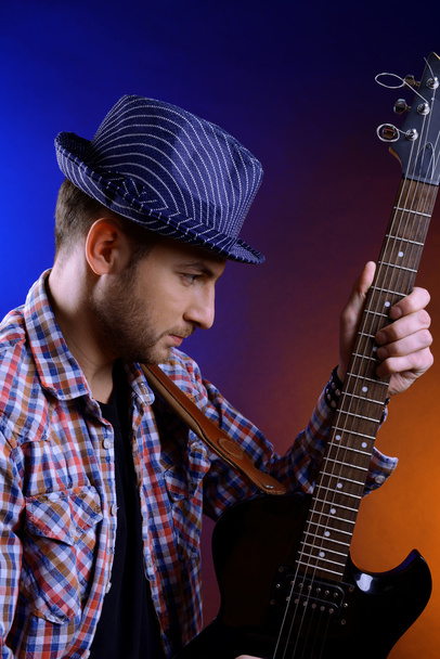 Young musician playing guitar on dark color background - Fotografie, Obrázek