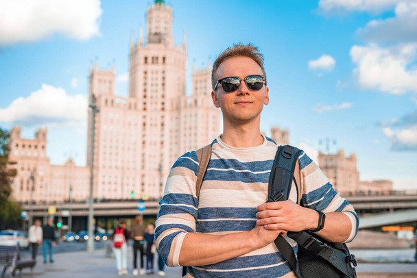  Portrait of a young blond man with the background of the famous high-rise building and the Moscow river on a Sunny summer day - Foto, imagen