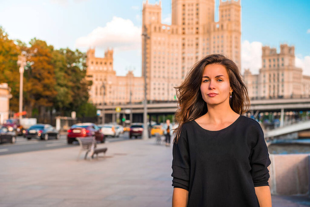 Portrait of a young brunette woman in a jacket with an inscription with the background of the famous high-rise building and the Moscow river on a Sunny summer day - Foto, Imagem