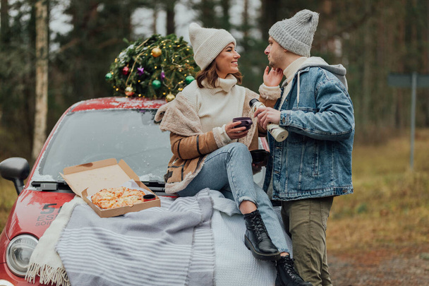 Winter love story of young couple, man and woman, christmas tree, outdoors - Foto, imagen