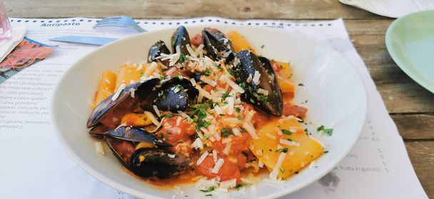 вкусное блюдо из paccheri allo scoglio с морепродуктами мидий и перкорино в осетии Рим. Высокое качество фото - Фото, изображение