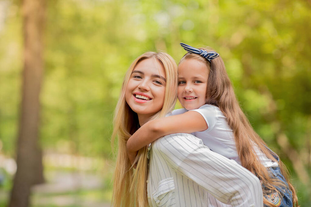 Mother Carrying Little Daughter Smiling To Camera Posing In Park - Photo, Image