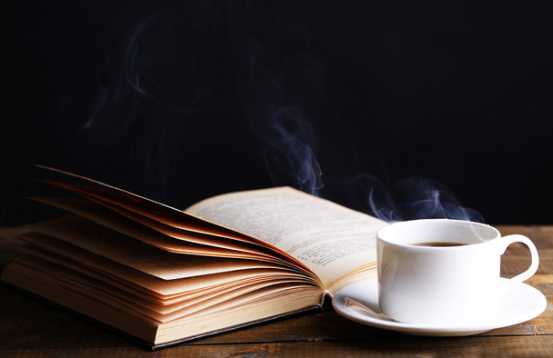 Cup of hot coffee with book on table on dark background - Photo, Image