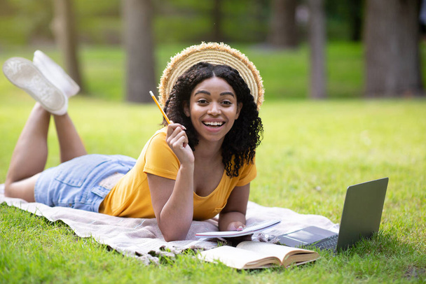 Pretty black girl having creative idea during her studies with laptop at park, free space - Photo, Image