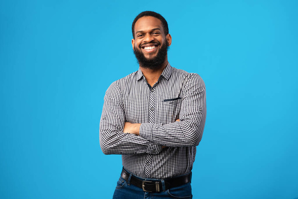 Lächelnder Afro-Mann posiert auf blauem Hintergrund - Foto, Bild