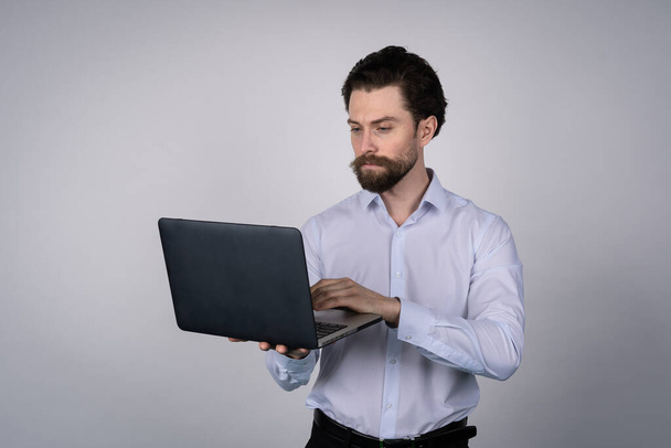 Портрет человека, работающего на ноутбуке в повседневных условиях - изолированный на белом. Концепция коммуникации. - Фото, изображение