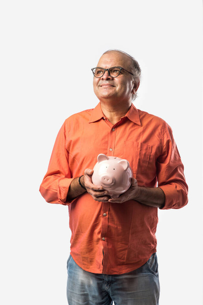 Indiase senior volwassen of oude man met spaarvarken bank of spaarpot - Foto, afbeelding
