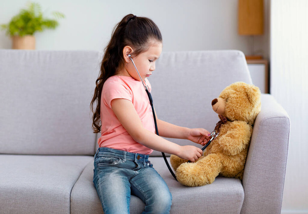 Imádnivaló kislány játszik orvos Teddy Bear otthon - Fotó, kép