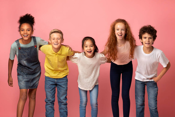 Портрет мультиэтнических школьников, улыбающихся на розовом фоне - Фото, изображение