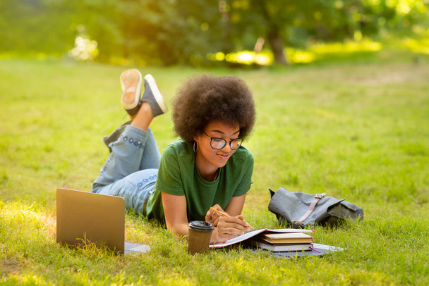 Concept d'éducation. Jeune étudiante noire étudiant en plein air avec des livres et un ordinateur portable - Photo, image