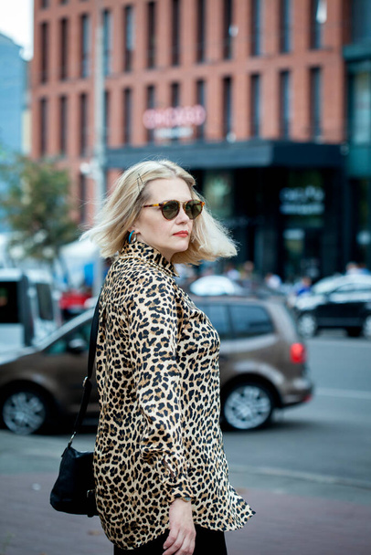 KIEV, UKRAINE - AUGUST 24, 2020: Outdoor close-up fashion portrait of young elegant lady in leopard print shirt posing on the street of European city. Copy space - Photo, Image