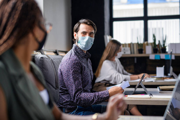 Portrait of young businesspeople with face masks working indoors in office. - Foto, Imagem