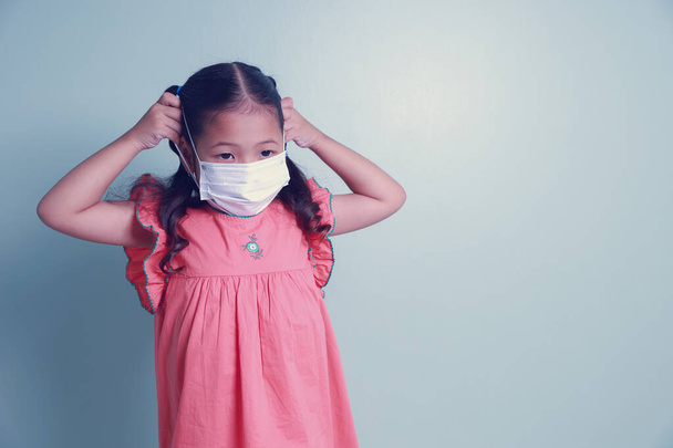 Portrait Asian kid girl wearing a medical mask for protection coronavirus Covid-19. Stop coronavirus outbreak has to keep social distances and wear a face mask every time they leave home. - Photo, Image