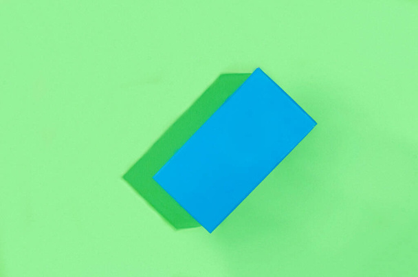 青の幾何学的図形、明るい緑の背景に影のある長方形。署名、モックアップのための空の場所と要約最小限のシーン - 写真・画像