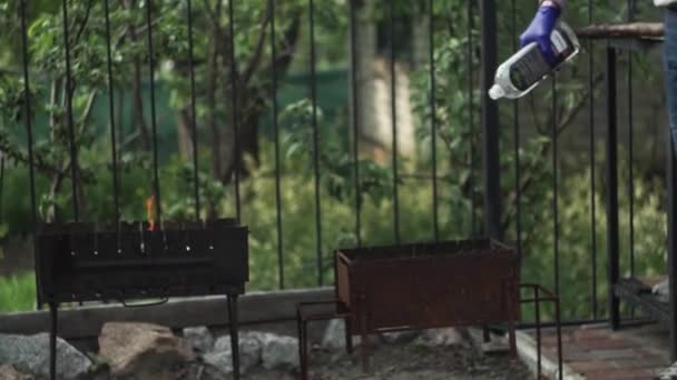 Hand in Hand mit Zündflüssigkeitsflasche, brennender Kamin Hintergrund aus nächster Nähe. - Filmmaterial, Video