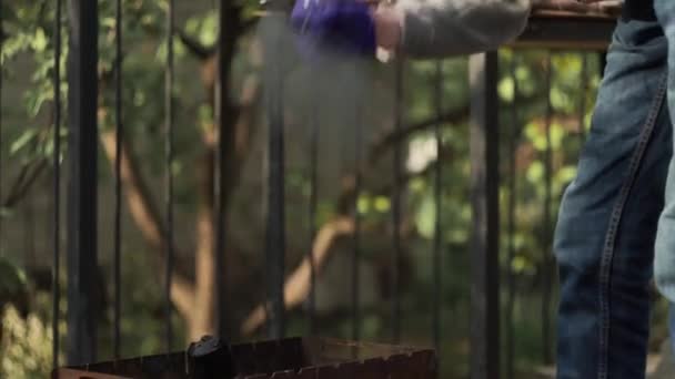 Primer plano. Fuego de abanico de mano, chispas de carbones, uso de pala en barbacoa con leña - Metraje, vídeo