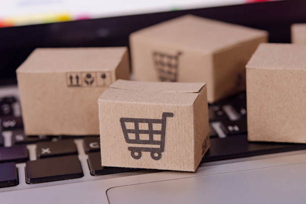 Online einkaufen. Karton mit einem Warenkorb-Logo auf der Laptop-Tastatur. Shopping-Service im Internet. bietet Hauszustellung - Foto, Bild